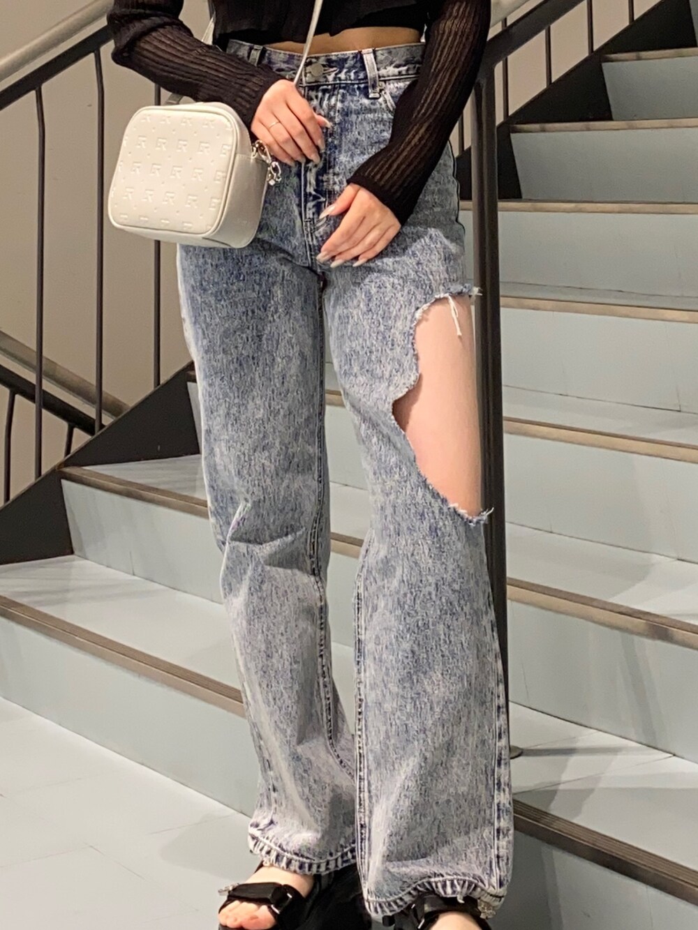 ブラック系のカーディガン/ボレロ、ブルー系のデニムパンツ、ブラック系のサンダルを着用したレディースの春コーディネートの4枚目の写真