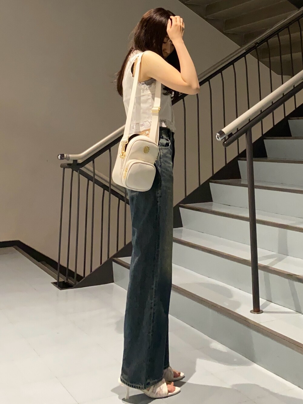 ブルー系のデニムパンツ、ホワイト系のサンダル、ホワイト系のシャツ/ブラウスを着用したレディースの夏コーディネートの2枚目の写真