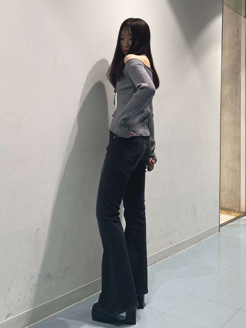 グレー系のニット/セーター、ブラック系のデニムパンツ、ブラック系のブーツを着用したレディースの秋コーディネートの2枚目の写真