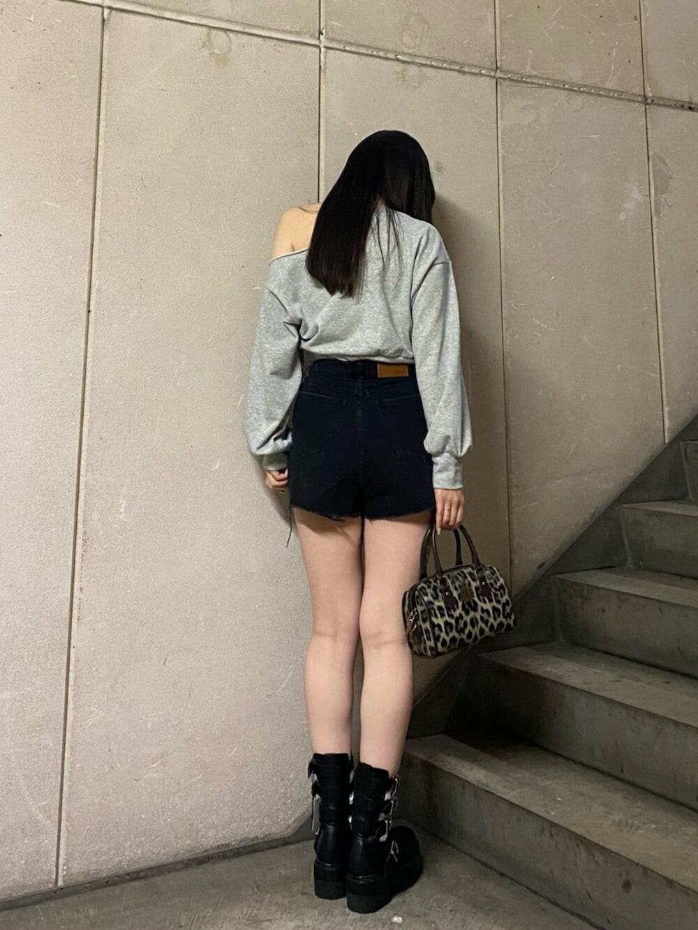 ブラック系のデニムパンツ、グレー系のスウェット、ブラック系のブーツを着用したレディースの春コーディネートの3枚目の写真