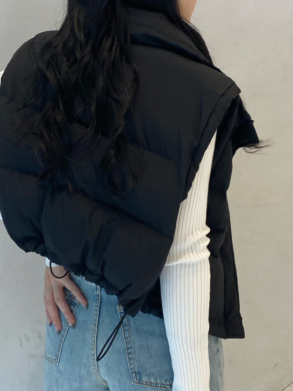 ブラック系のダウンベスト、ブルー系のデニムパンツ、ベージュ系のスリッポンを着用したレディースの秋コーディネートの3枚目の写真