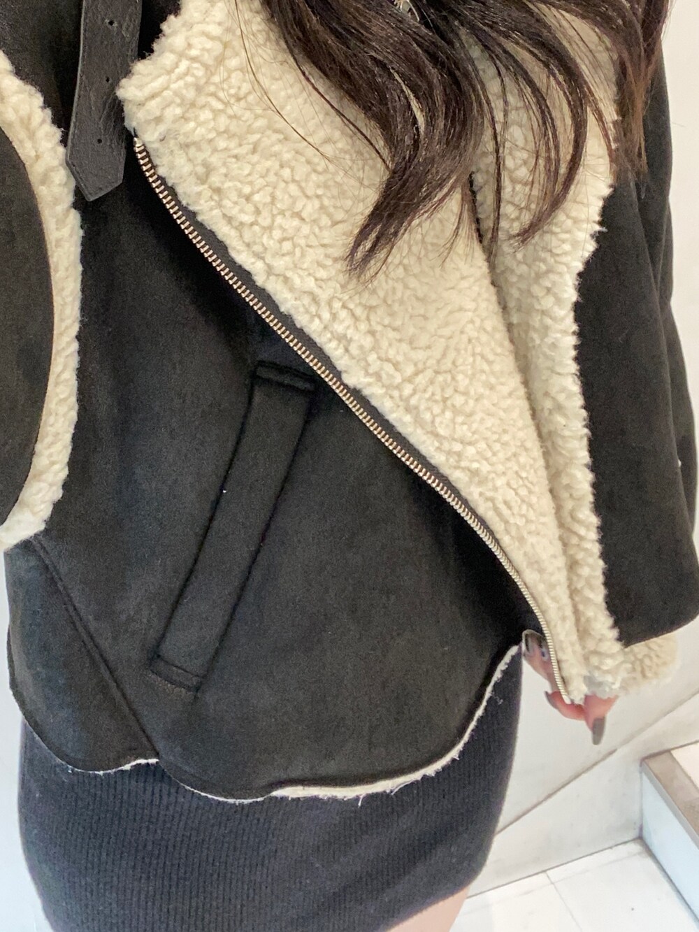 ブラック系のムートンコート、ブラック系のワンピース、ブラック系のハンドバッグを着用したレディースの秋コーディネートの5枚目の写真