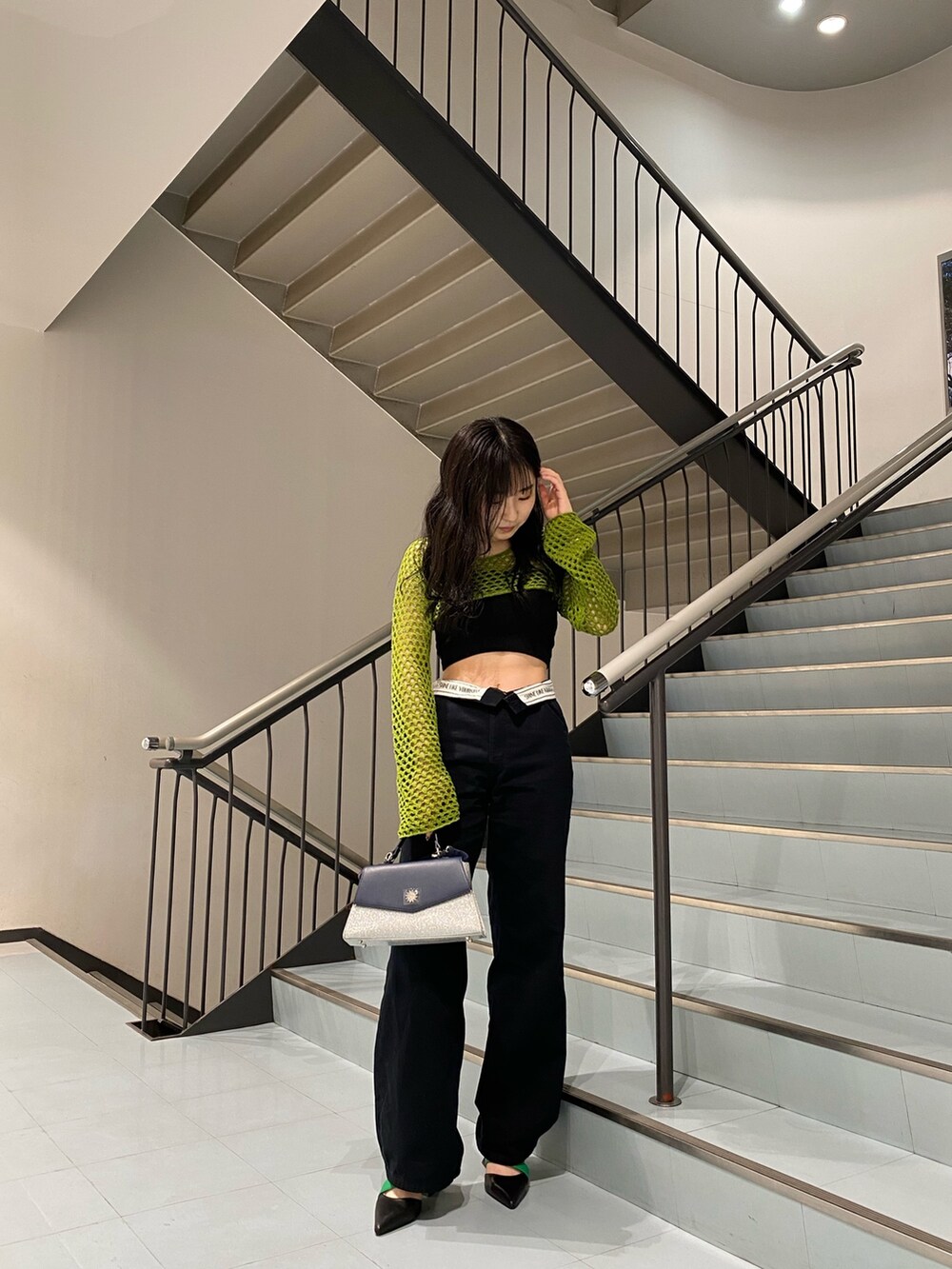 グリーン系のニット/セーター、ブラック系のサンダル、シルバー系のショルダーバッグを着用したレディースの春コーディネートの2枚目の写真