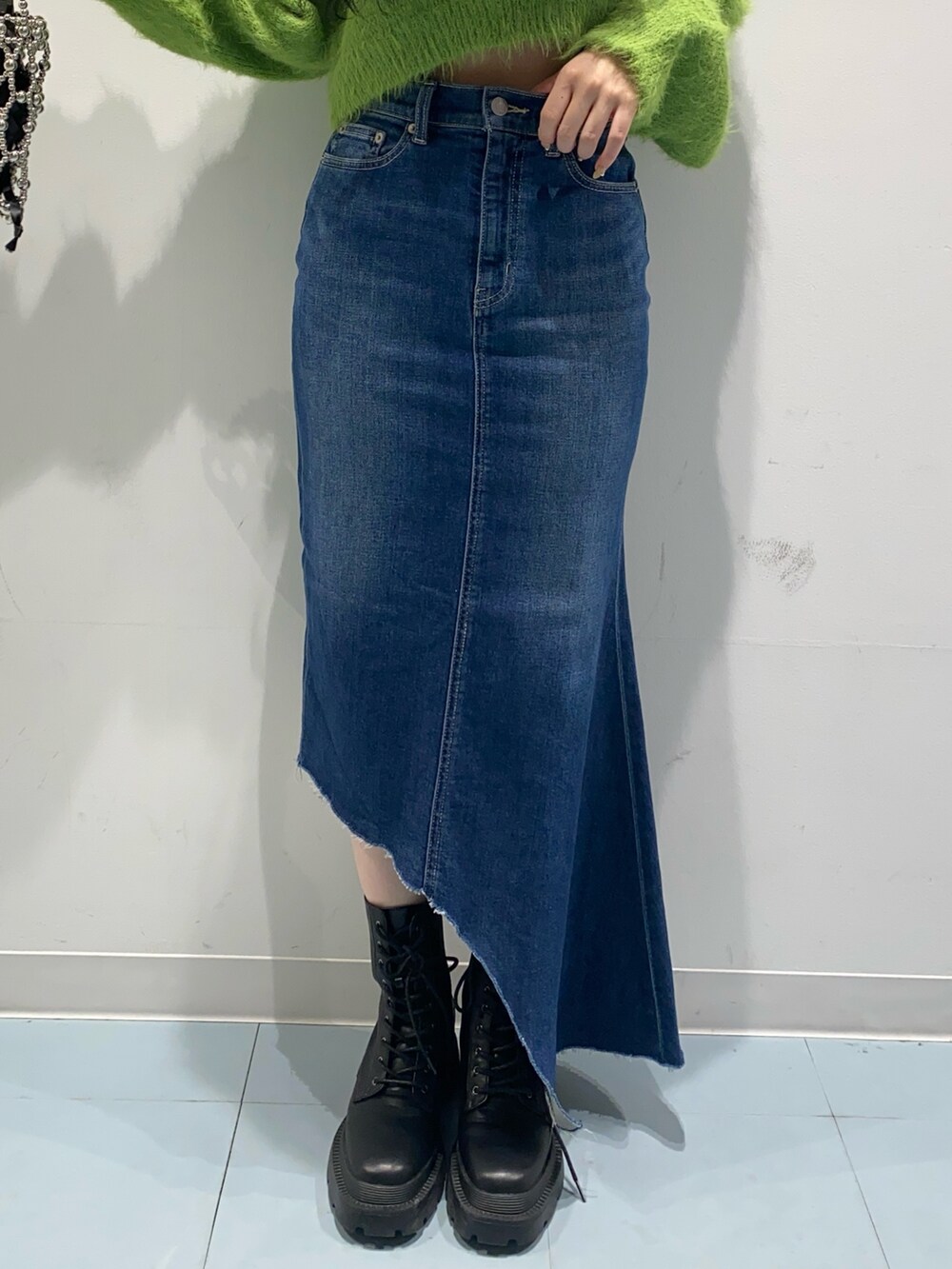 グリーン系のニット/セーター、ブルー系のデニムスカート、ブラック系のブーツを着用したレディースの冬コーディネートの4枚目の写真