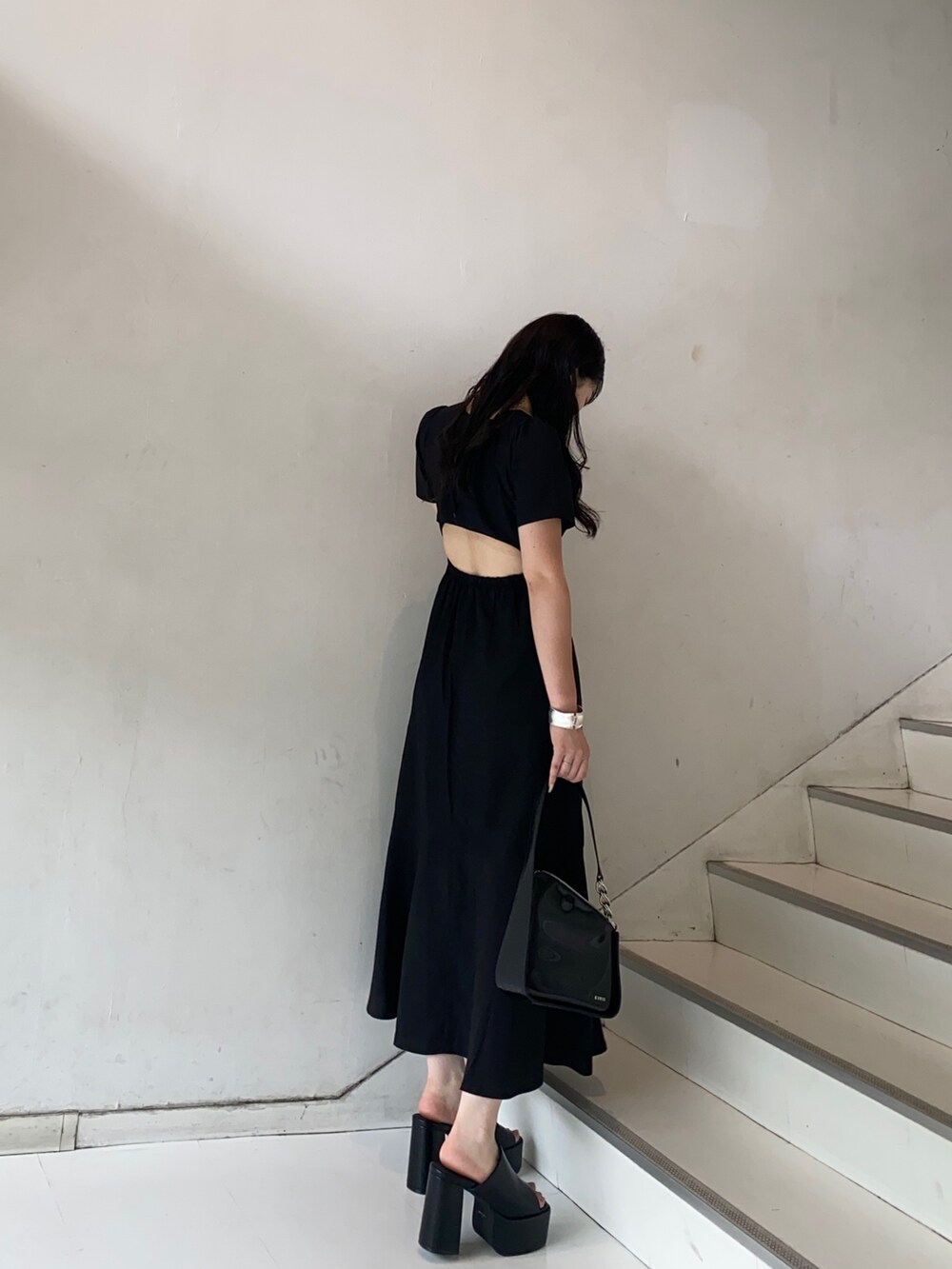 ブラック系のワンピース、ブラック系のサンダル、ブラック系のハンドバッグを着用したレディースの夏コーディネートの2枚目の写真