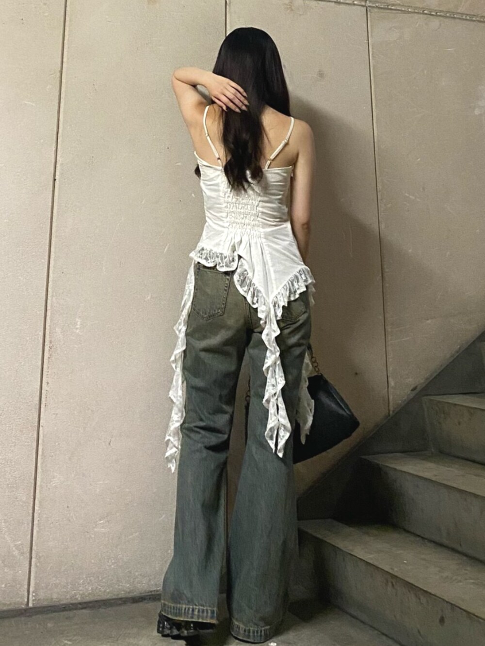 ブラック系のハンドバッグ、ホワイト系のキャミソール、ブルー系のデニムパンツを着用したレディースの夏コーディネートの3枚目の写真