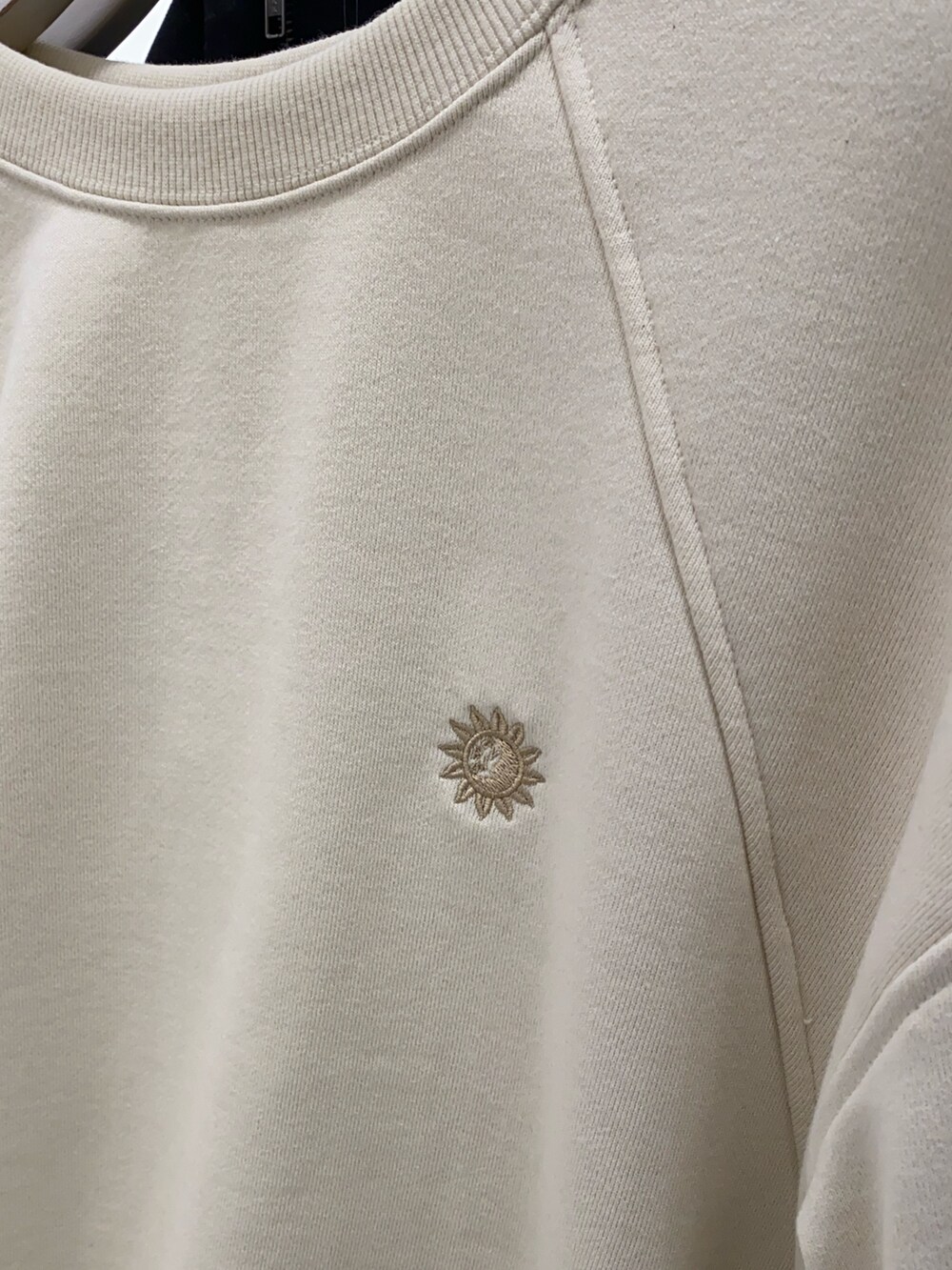 ホワイト系のスウェット、ブラック系のショルダーバッグ、ブラック系のブーツを着用したレディースの冬コーディネートの3枚目の写真