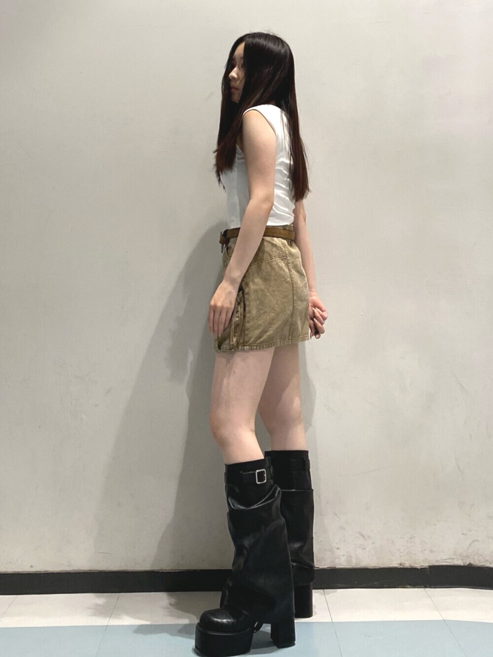 ブラック系のブーツ、ホワイト系のタンクトップ、ベージュ系のスカートを着用したレディースの夏コーディネートの2枚目の写真