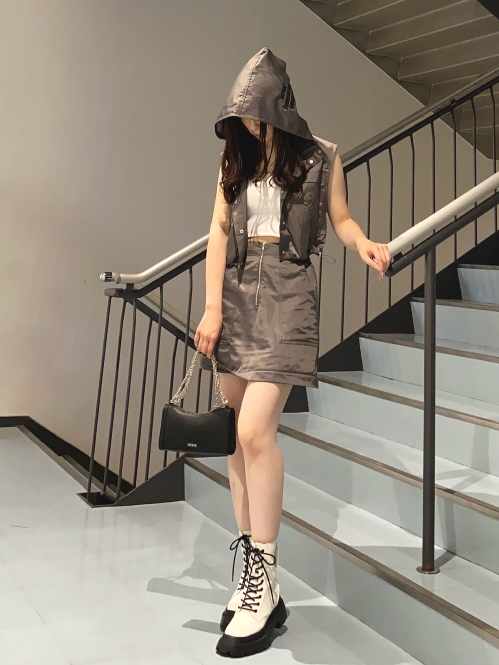 グレー系のベスト、グレー系のスカート、ブラック系のショルダーバッグを着用したレディースの夏コーディネートの4枚目の写真