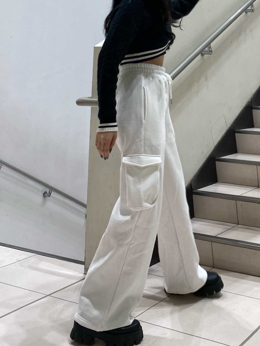 ブラック系のニット/セーター、ホワイト系のスウェットパンツ、ブラック系のハンドバッグを着用したレディースの秋コーディネートの7枚目の写真