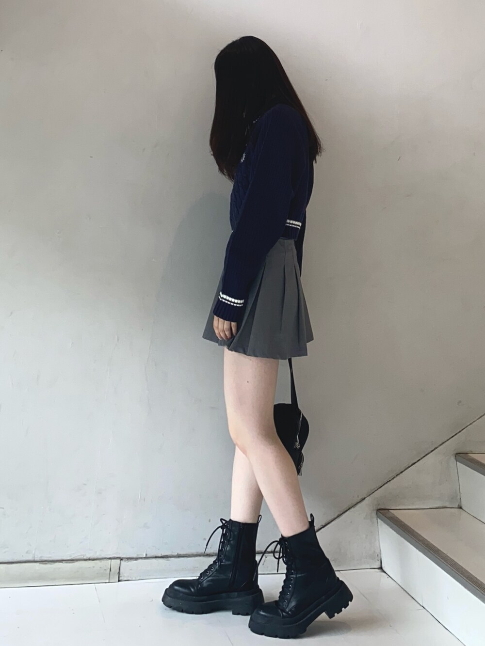 グレー系のスカート、ブルー系のニット/セーター、ブラック系のショルダーバッグを着用したレディースの夏コーディネートの2枚目の写真