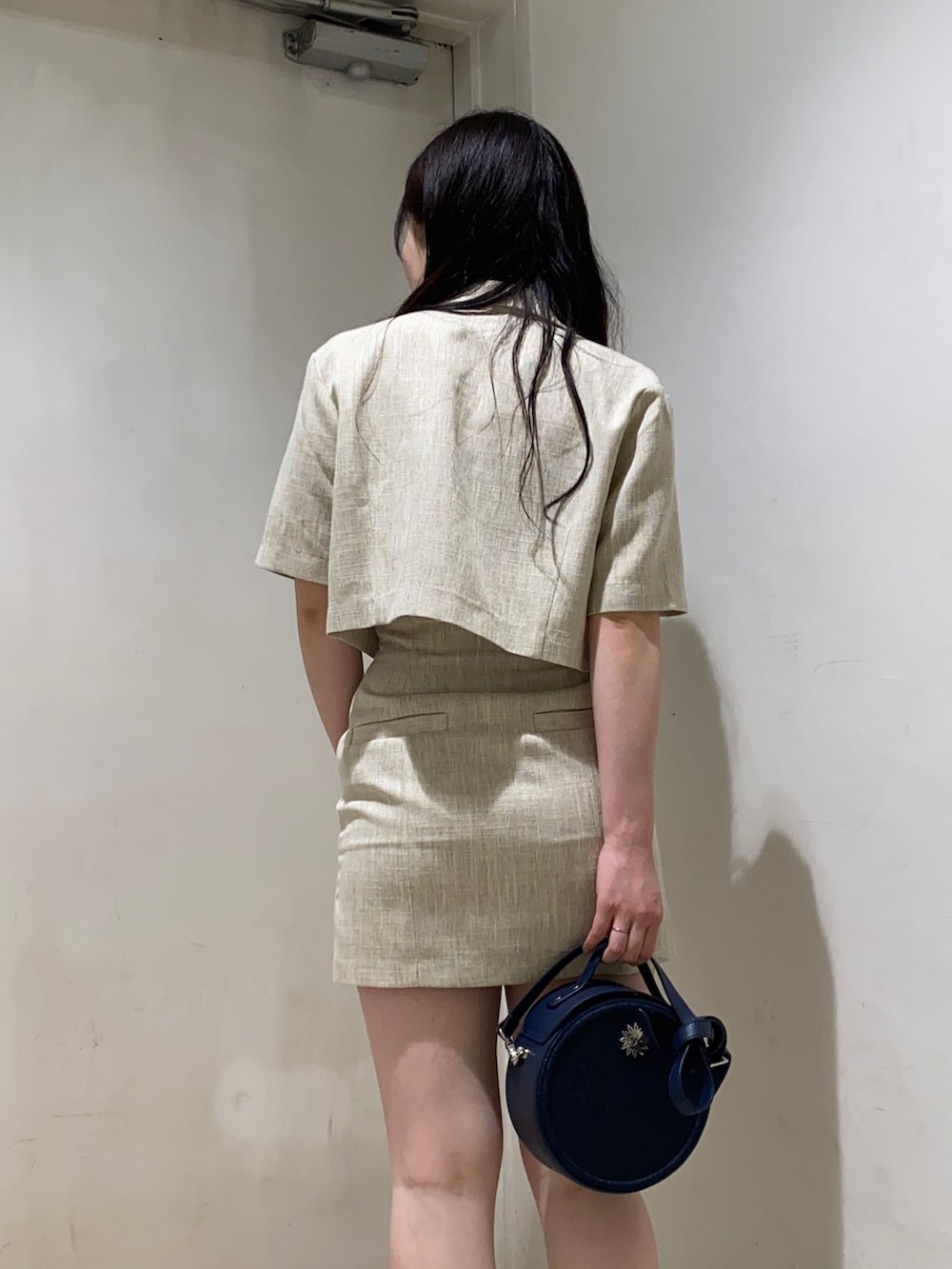 ホワイト系のテーラードジャケット、ホワイト系のスカート、ブラック系のサンダルを着用したレディースの春コーディネートの2枚目の写真