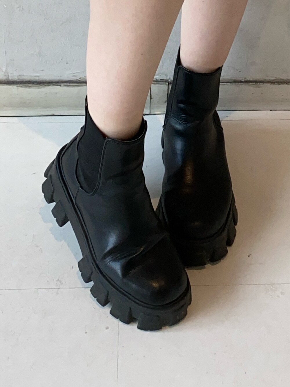 ホワイト系のスウェット、ブラック系のショルダーバッグ、ブラック系のブーツを着用したレディースの冬コーディネートの6枚目の写真