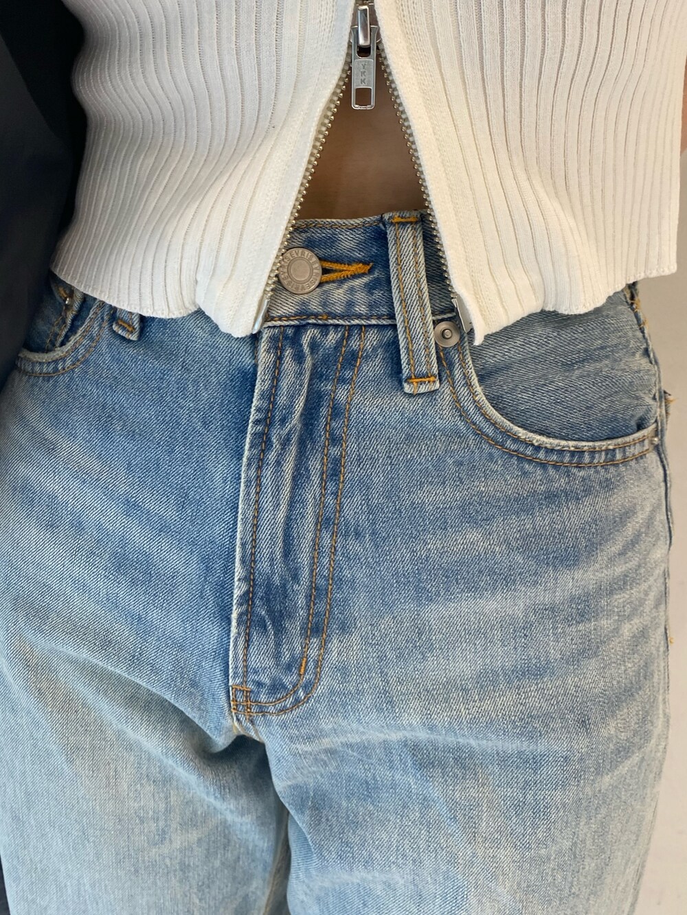 ブラック系のダウンベスト、ブルー系のデニムパンツ、ベージュ系のスリッポンを着用したレディースの秋コーディネートの5枚目の写真