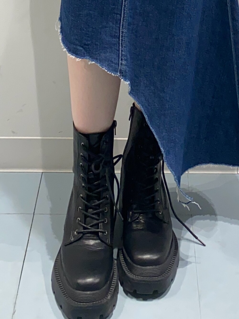 グリーン系のニット/セーター、ブルー系のデニムスカート、ブラック系のブーツを着用したレディースの冬コーディネートの5枚目の写真