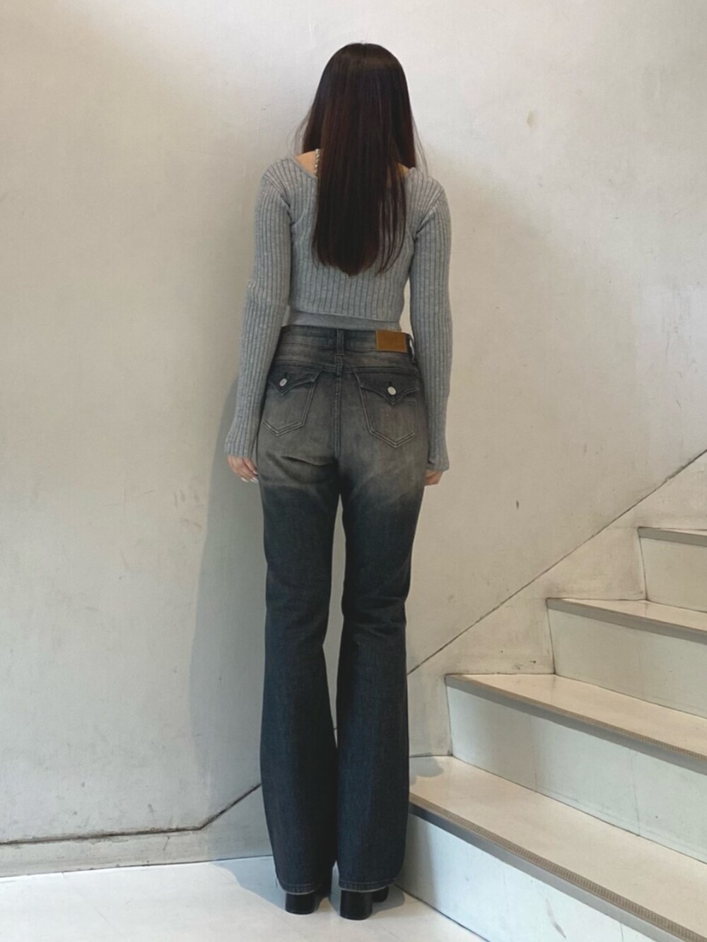 グレー系のニット/セーター、ブラック系のデニムパンツ、ブラック系のブーツを着用したレディースの秋コーディネートの3枚目の写真