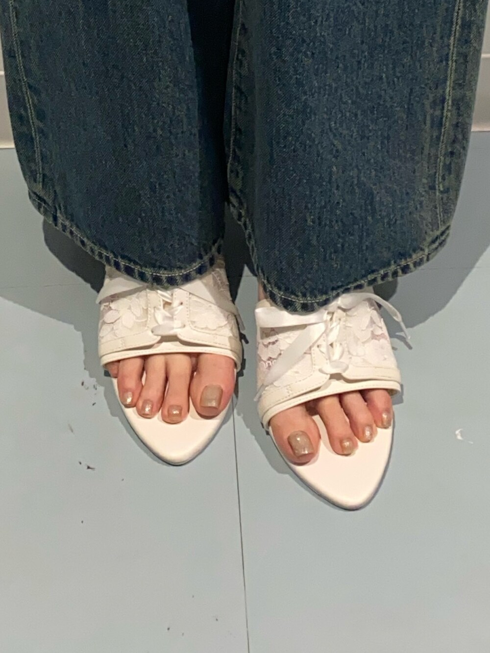 ブルー系のデニムパンツ、ホワイト系のサンダル、ホワイト系のシャツ/ブラウスを着用したレディースの夏コーディネートの7枚目の写真