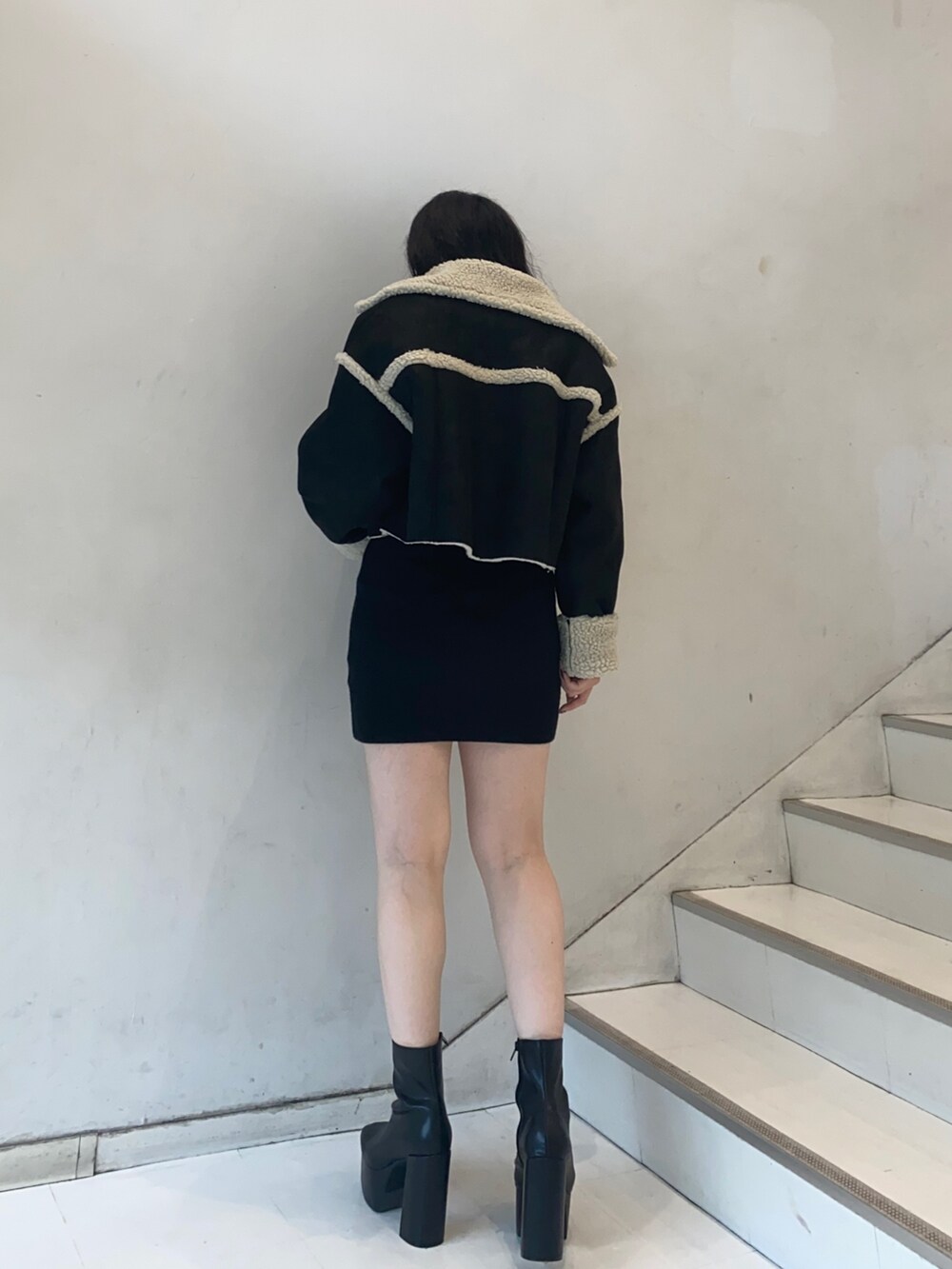 ブラック系のムートンコート、ブラック系のワンピース、ブラック系のハンドバッグを着用したレディースの秋コーディネートの2枚目の写真