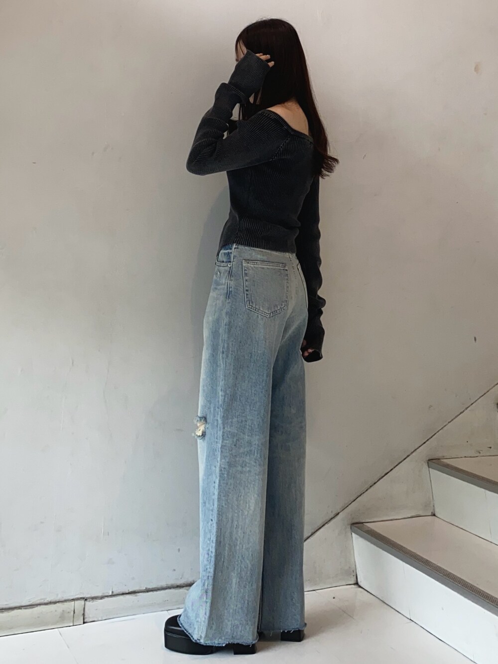 ブラック系のニット/セーター、ブルー系のデニムパンツ、ブラック系のブーツを着用したレディースの秋コーディネートの3枚目の写真