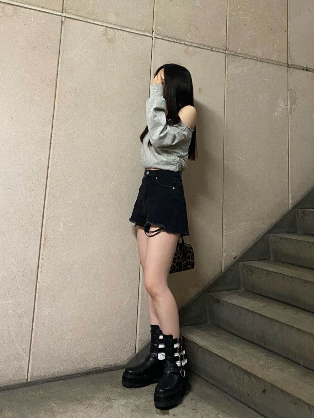 ブラック系のデニムパンツ、グレー系のスウェット、ブラック系のブーツを着用したレディースの春コーディネートの2枚目の写真