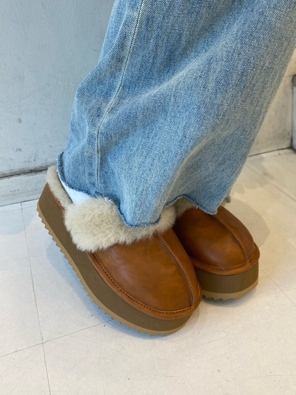 ブラック系のダウンベスト、ブルー系のデニムパンツ、ベージュ系のスリッポンを着用したレディースの秋コーディネートの6枚目の写真