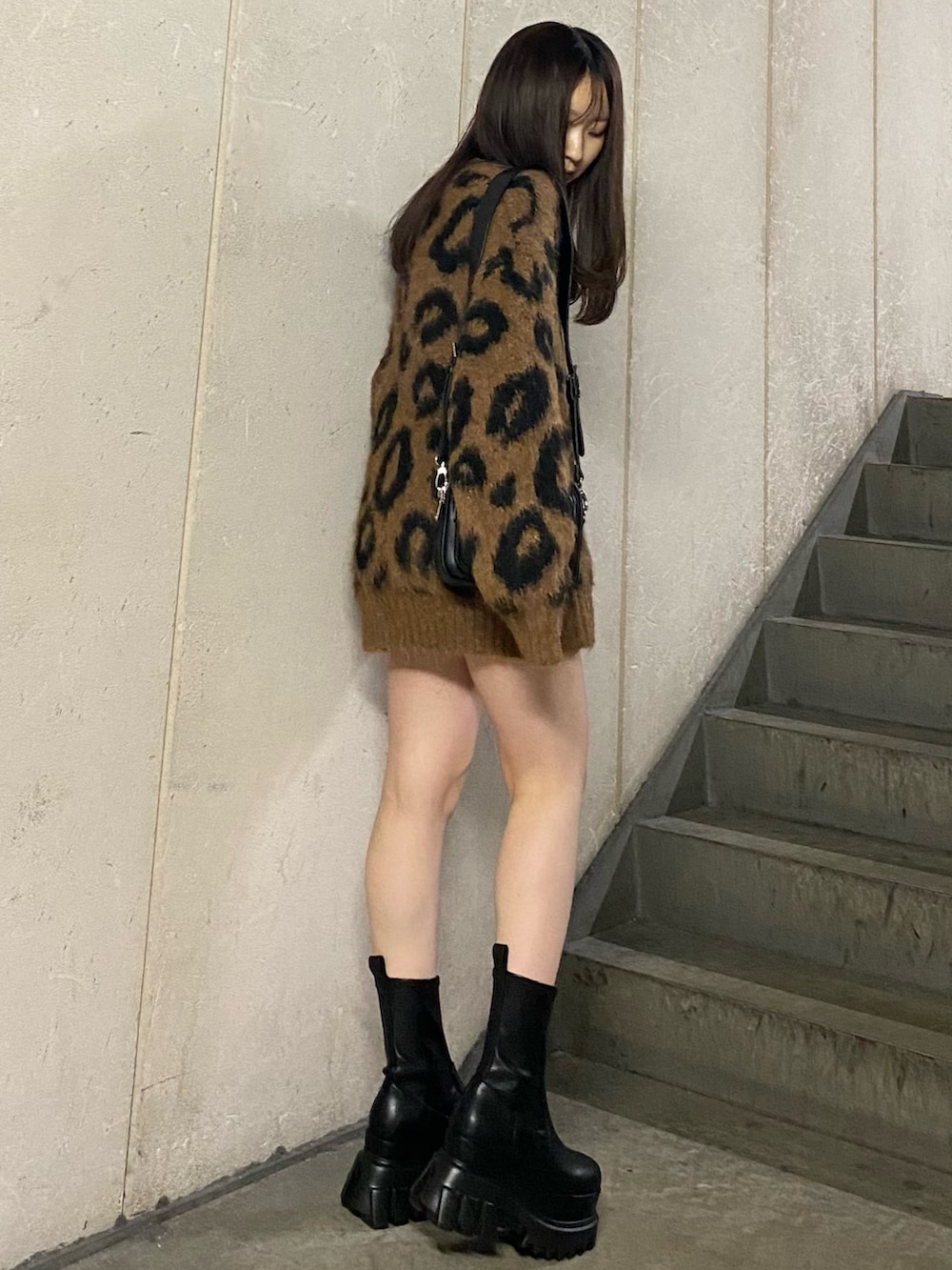 ブラック系のブーツ、ブラウン系のニット/セーター、ブラック系のショルダーバッグを着用したレディースの秋コーディネートの2枚目の写真