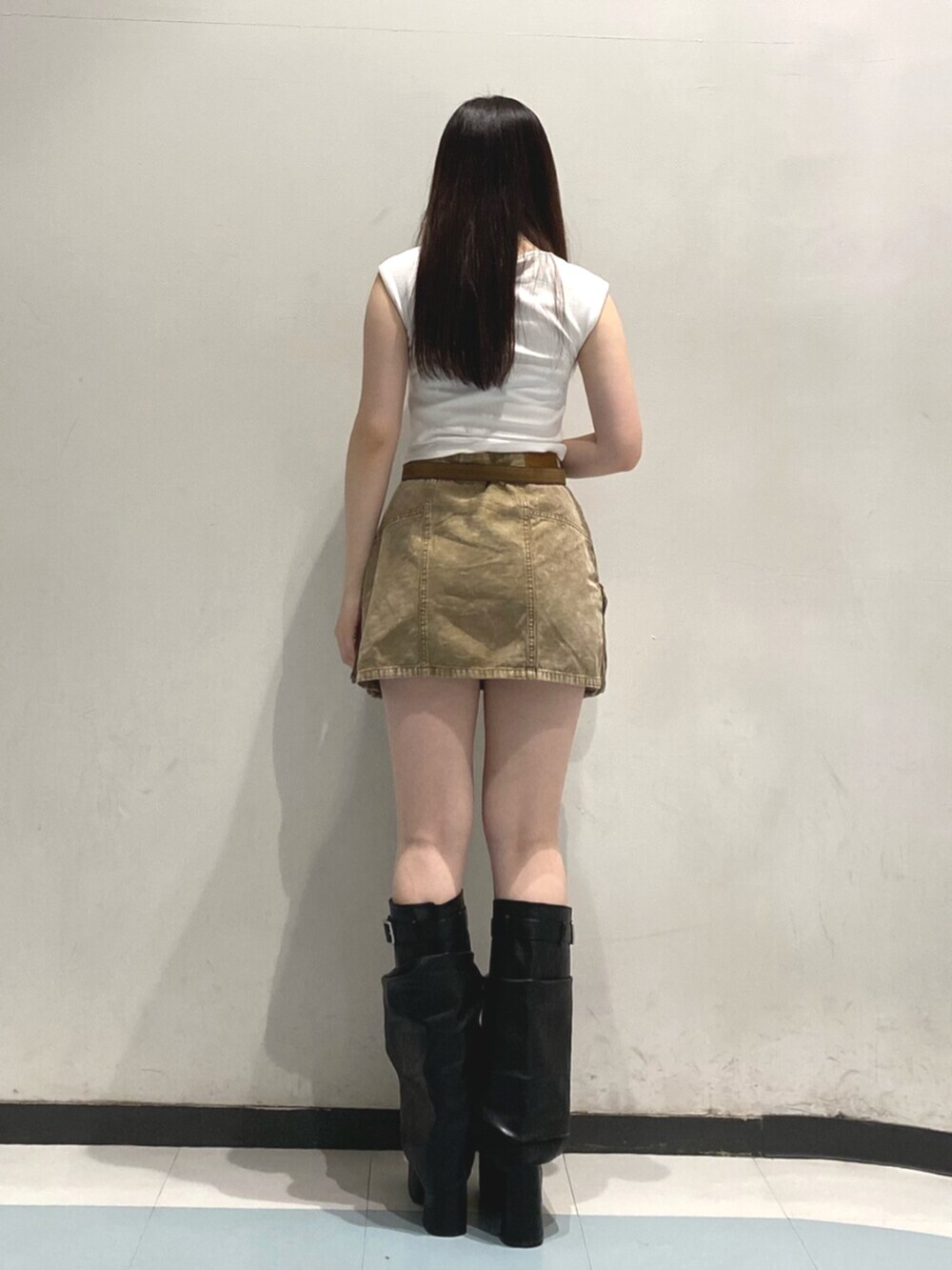 ブラック系のブーツ、ホワイト系のタンクトップ、ベージュ系のスカートを着用したレディースの夏コーディネートの3枚目の写真