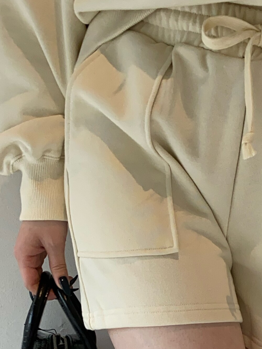 ホワイト系のスウェット、ブラック系のショルダーバッグ、ブラック系のブーツを着用したレディースの冬コーディネートの5枚目の写真