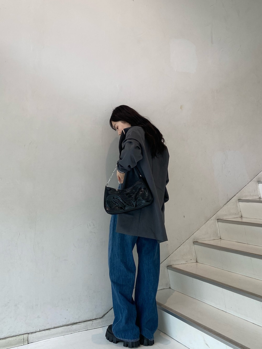 グレー系のテーラードジャケット、ブルー系のデニムパンツ、ブラック系のブーツを着用したレディースの秋コーディネートの2枚目の写真