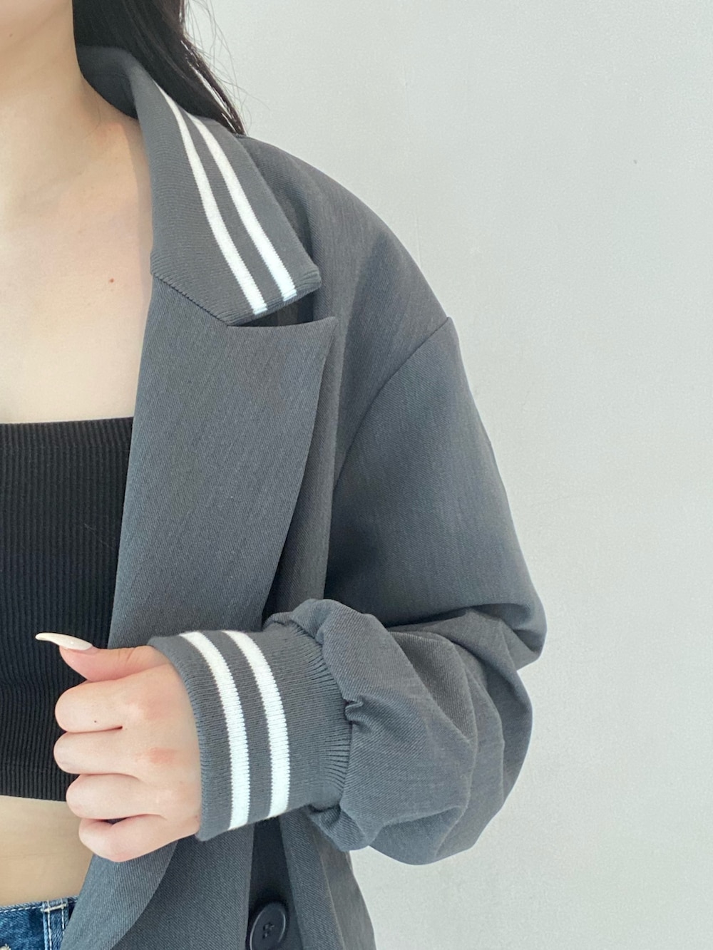 グレー系のテーラードジャケット、ブルー系のデニムパンツ、ブラック系のブーツを着用したレディースの秋コーディネートの3枚目の写真