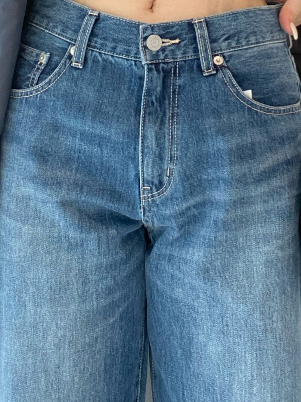 グレー系のテーラードジャケット、ブルー系のデニムパンツ、ブラック系のブーツを着用したレディースの秋コーディネートの4枚目の写真