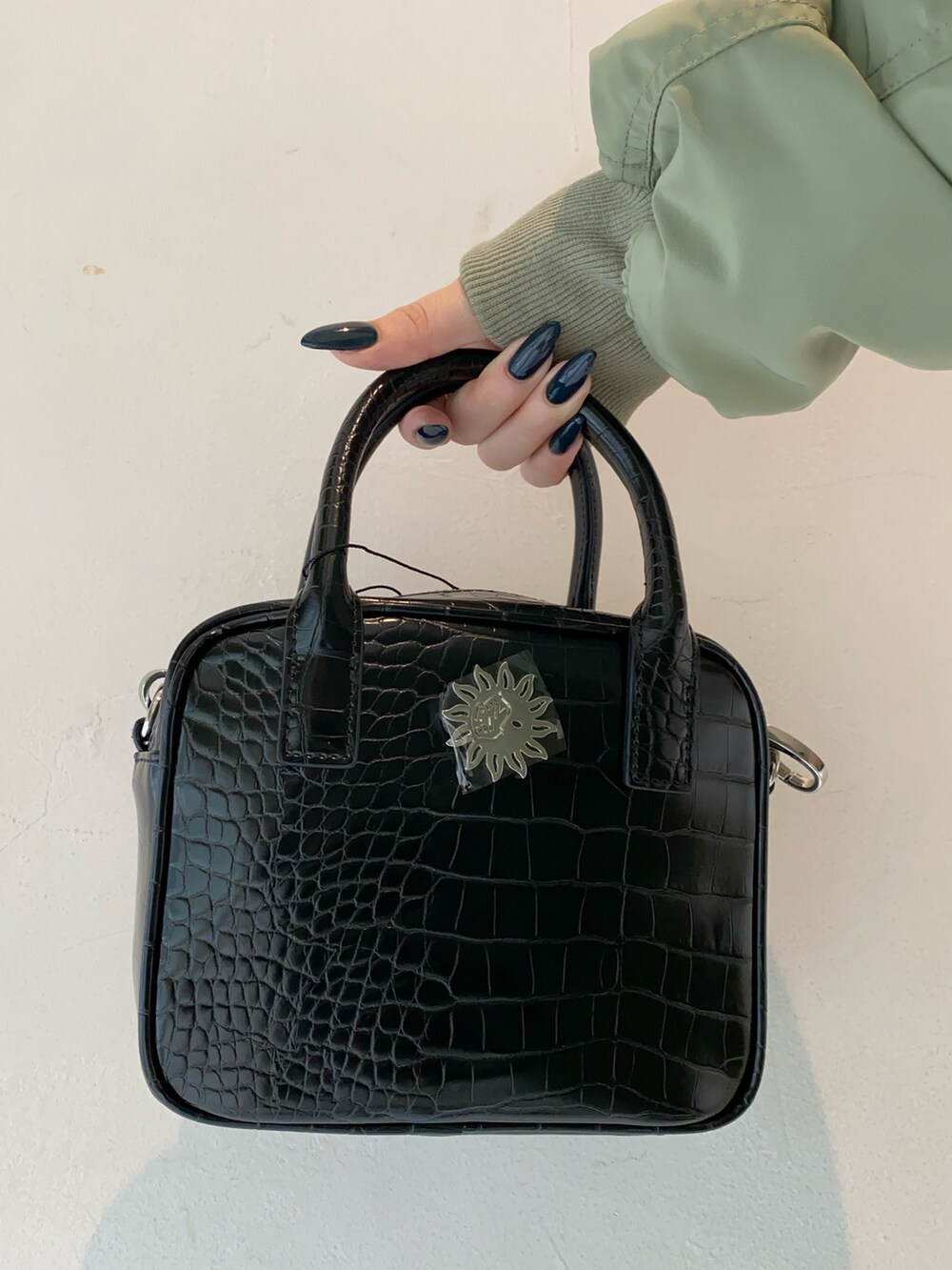 ホワイト系のスウェット、ブラック系のショルダーバッグ、ブラック系のブーツを着用したレディースの冬コーディネートの7枚目の写真