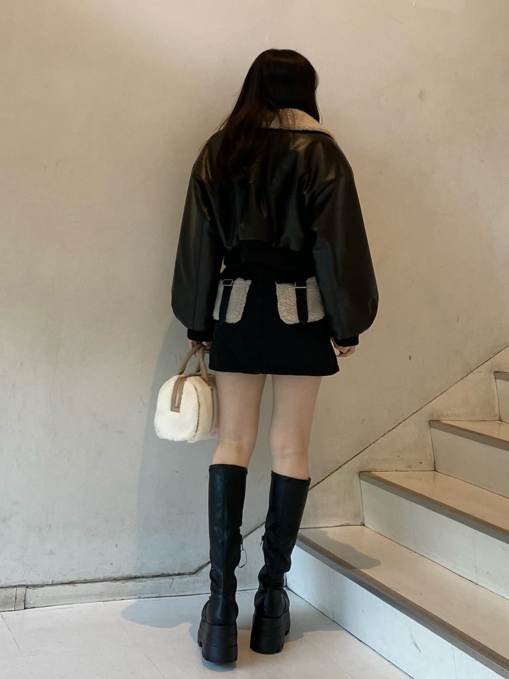 ブラック系のブーツ、ブラック系のデニムスカート、ホワイト系のボストンバッグを着用したレディースの冬コーディネートの3枚目の写真