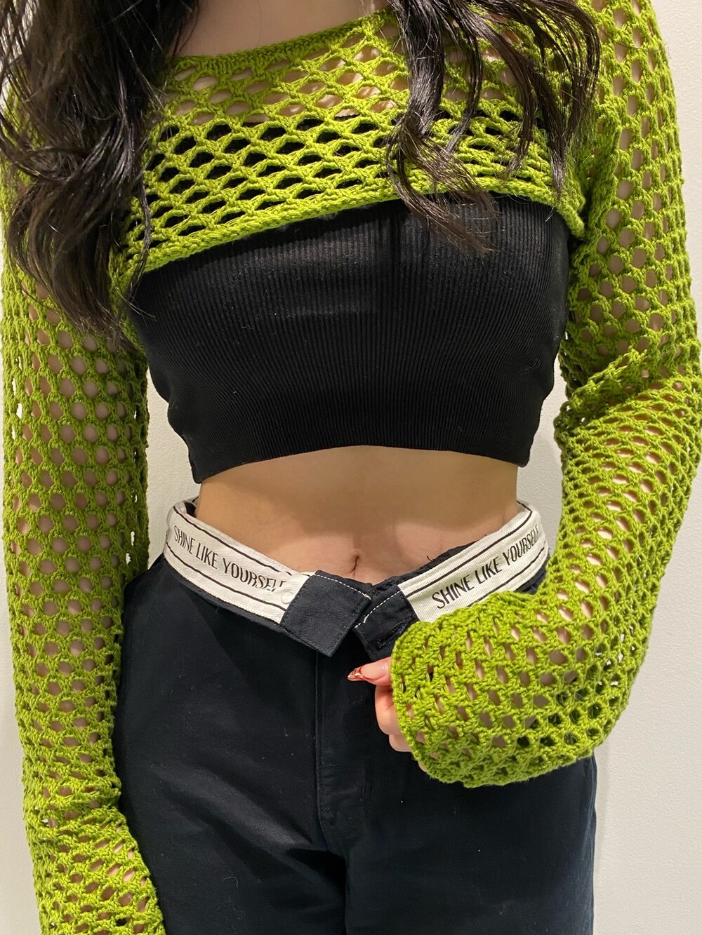 グリーン系のニット/セーター、ブラック系のサンダル、シルバー系のショルダーバッグを着用したレディースの春コーディネートの4枚目の写真