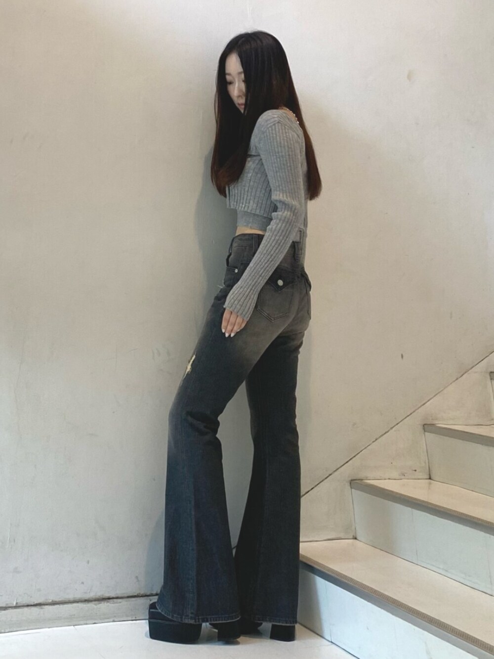 グレー系のニット/セーター、ブラック系のデニムパンツ、ブラック系のブーツを着用したレディースの秋コーディネートの2枚目の写真