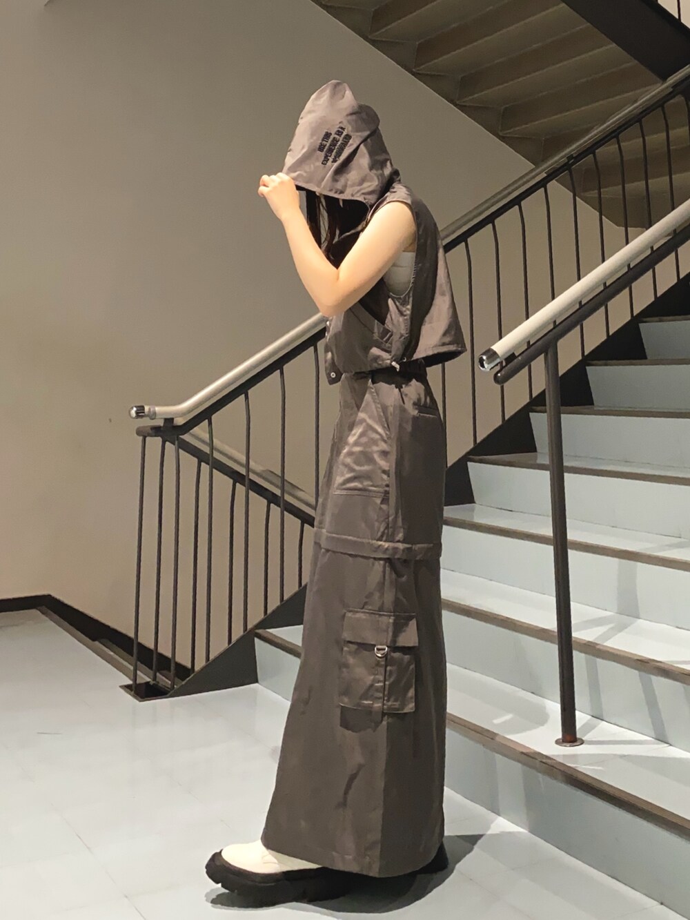 グレー系のベスト、グレー系のスカート、ブラック系のショルダーバッグを着用したレディースの夏コーディネートの2枚目の写真