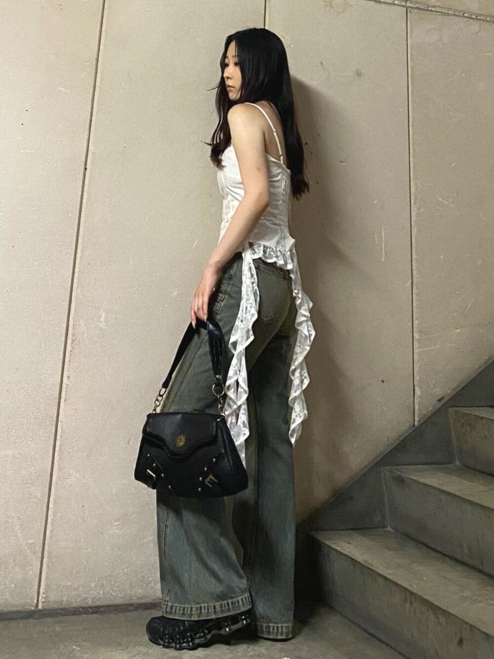 ブラック系のハンドバッグ、ホワイト系のキャミソール、ブルー系のデニムパンツを着用したレディースの夏コーディネートの2枚目の写真