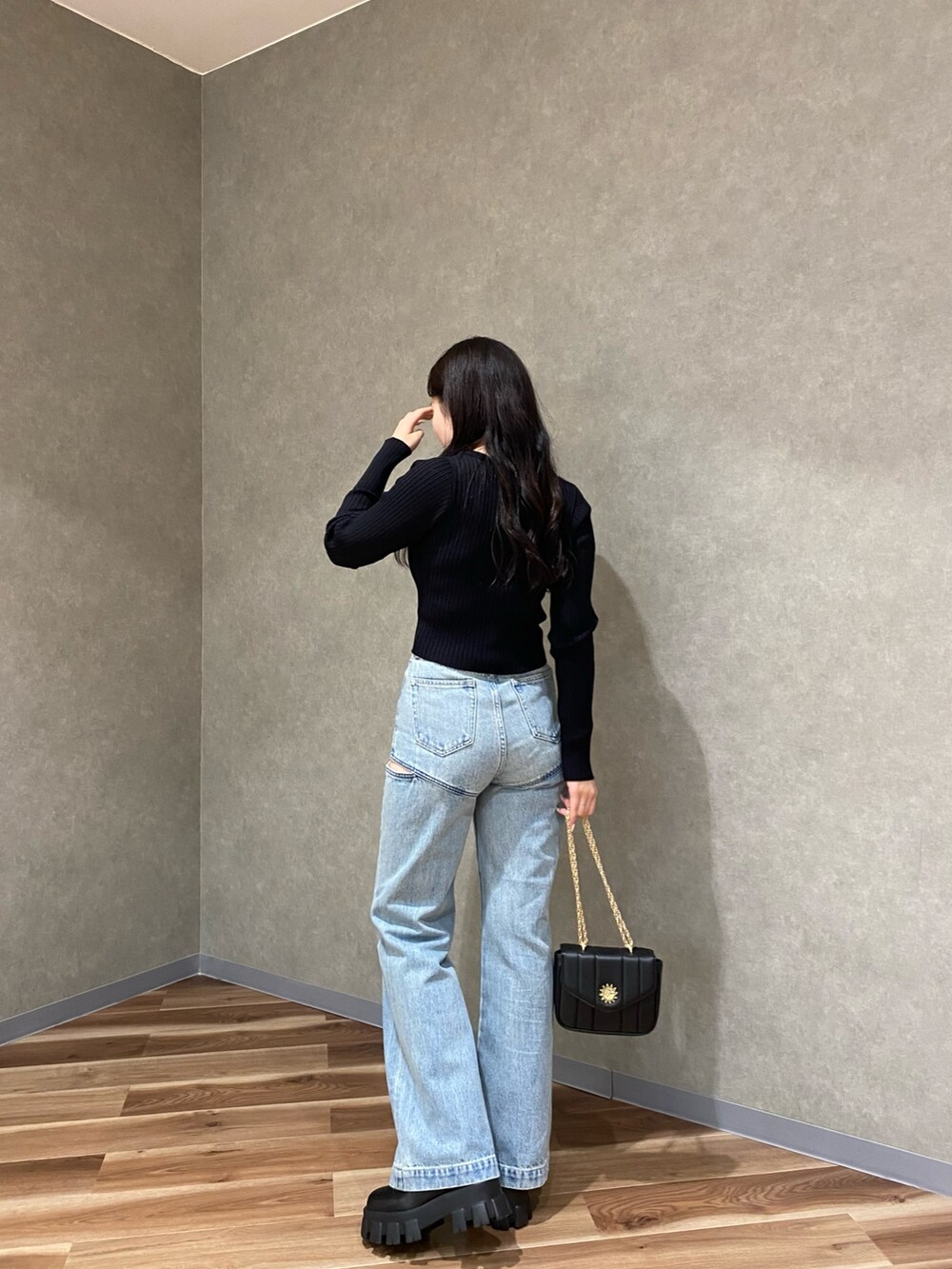 ブラック系のカーディガン/ボレロ、ブルー系のデニムパンツ、ブラック系のブーツを着用したレディースの秋コーディネートの2枚目の写真