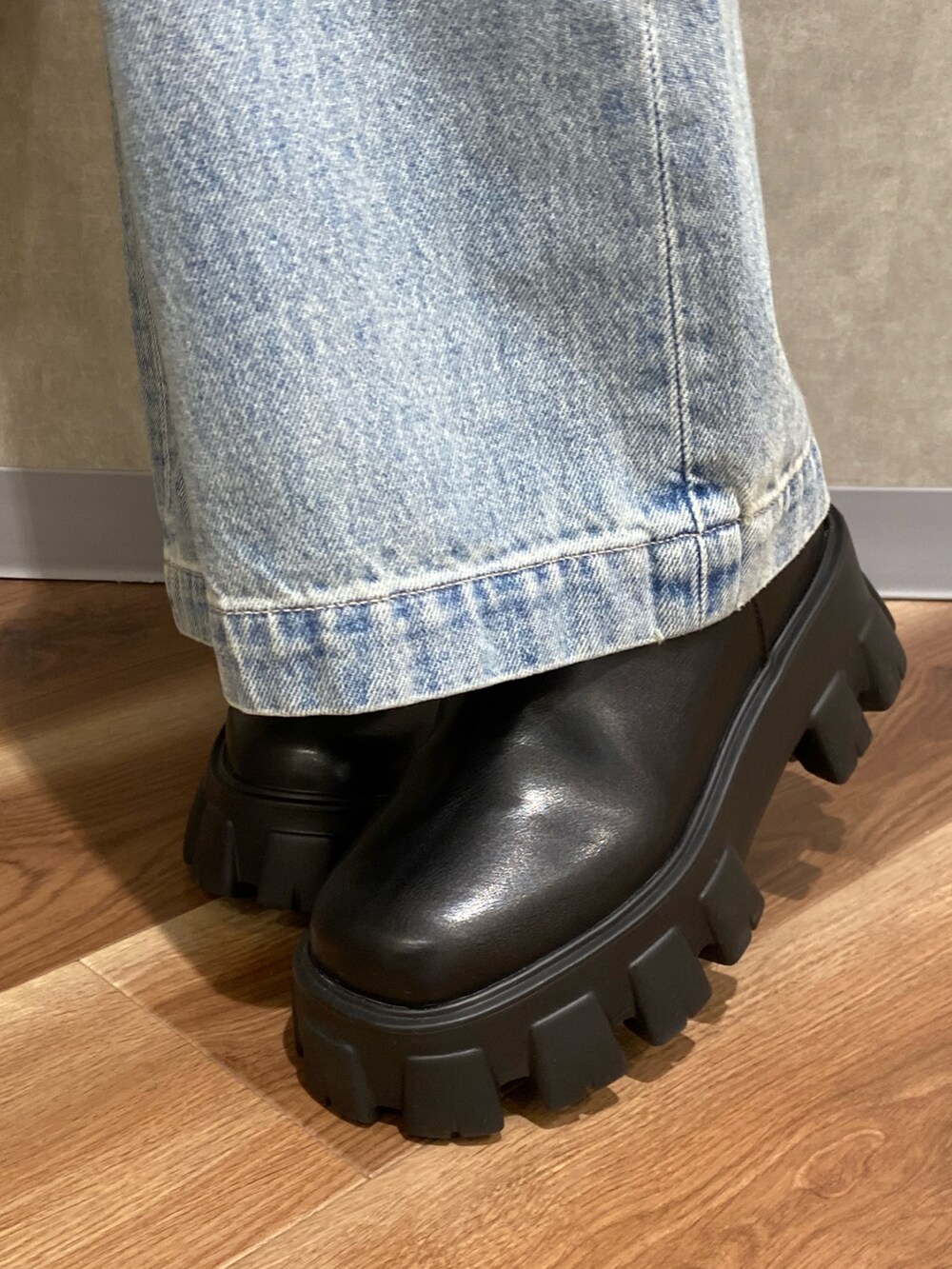 ブラック系のカーディガン/ボレロ、ブルー系のデニムパンツ、ブラック系のブーツを着用したレディースの秋コーディネートの6枚目の写真