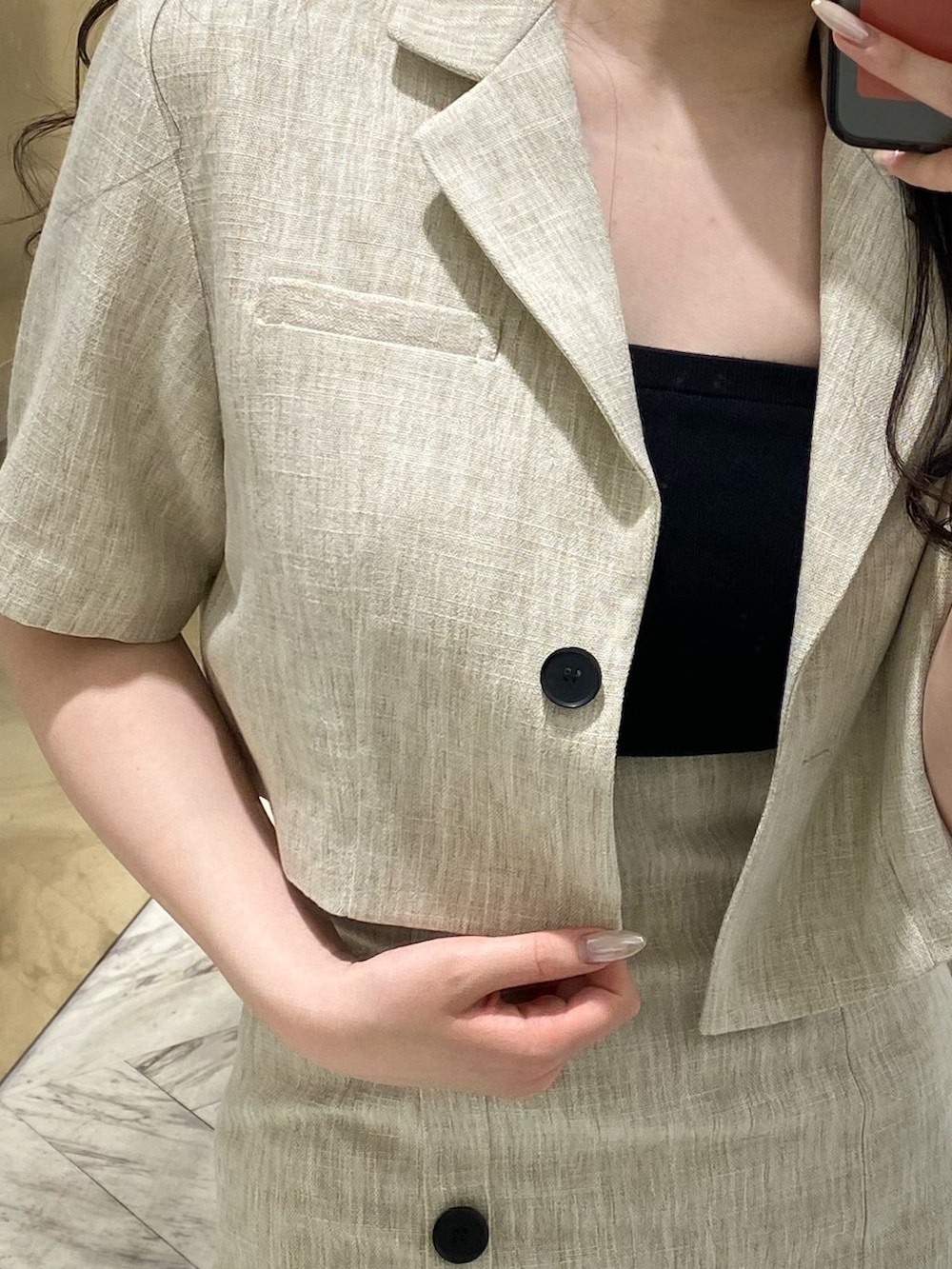 ホワイト系のテーラードジャケット、ホワイト系のスカート、ブラック系のサンダルを着用したレディースの春コーディネートの4枚目の写真