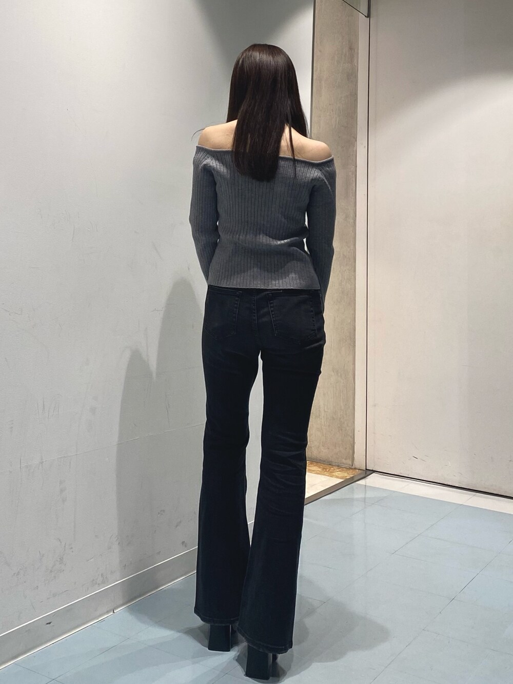 グレー系のニット/セーター、ブラック系のデニムパンツ、ブラック系のブーツを着用したレディースの秋コーディネートの3枚目の写真