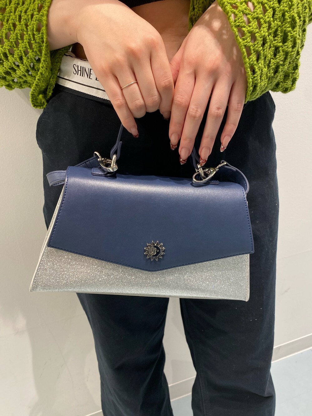 グリーン系のニット/セーター、ブラック系のサンダル、シルバー系のショルダーバッグを着用したレディースの春コーディネートの6枚目の写真