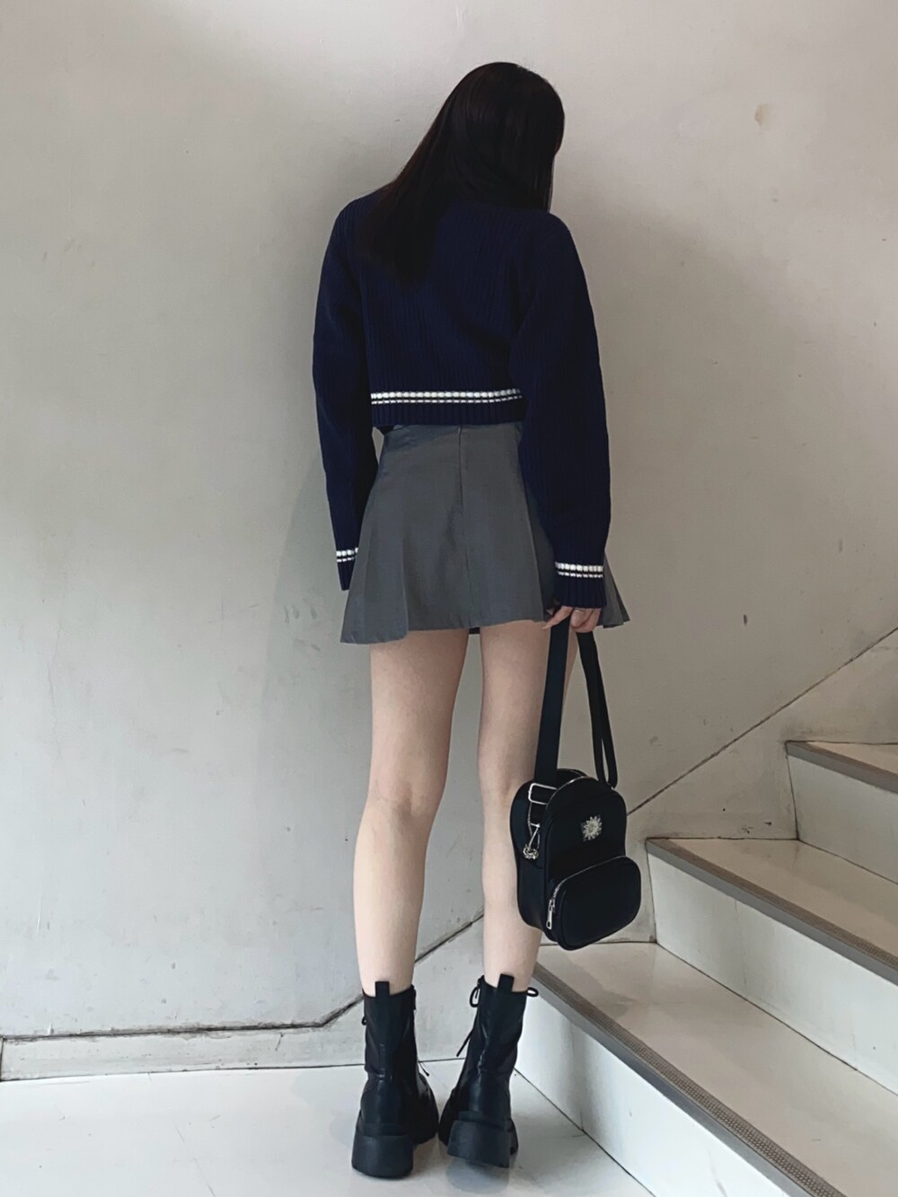 グレー系のスカート、ブルー系のニット/セーター、ブラック系のショルダーバッグを着用したレディースの夏コーディネートの3枚目の写真