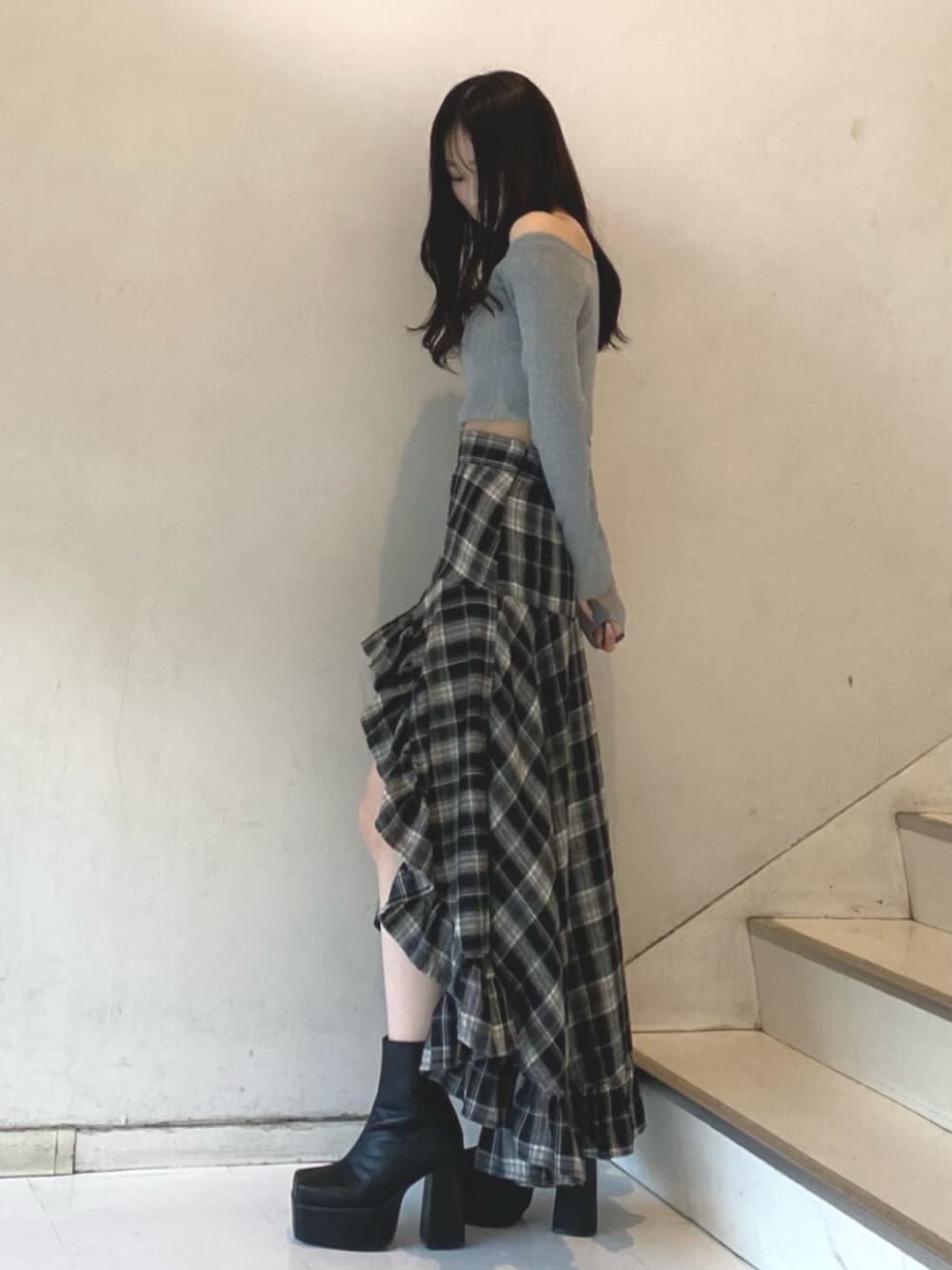 グレー系のニット/セーター、ブラック系のスカート、ブラック系のブーツを着用したレディースの冬コーディネートの2枚目の写真