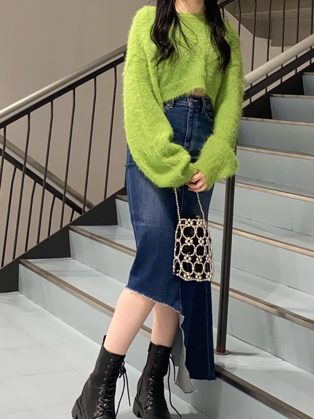 グリーン系のニット/セーター、ブルー系のデニムスカート、ブラック系のブーツを着用したレディースの冬コーディネートの3枚目の写真