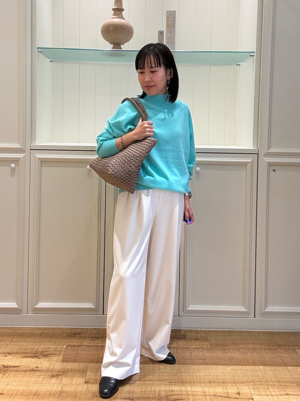 グリーン系のニット/セーター、ベージュ系のトートバッグ、ホワイト系のその他パンツを着用したレディースの秋コーディネートの3枚目の写真