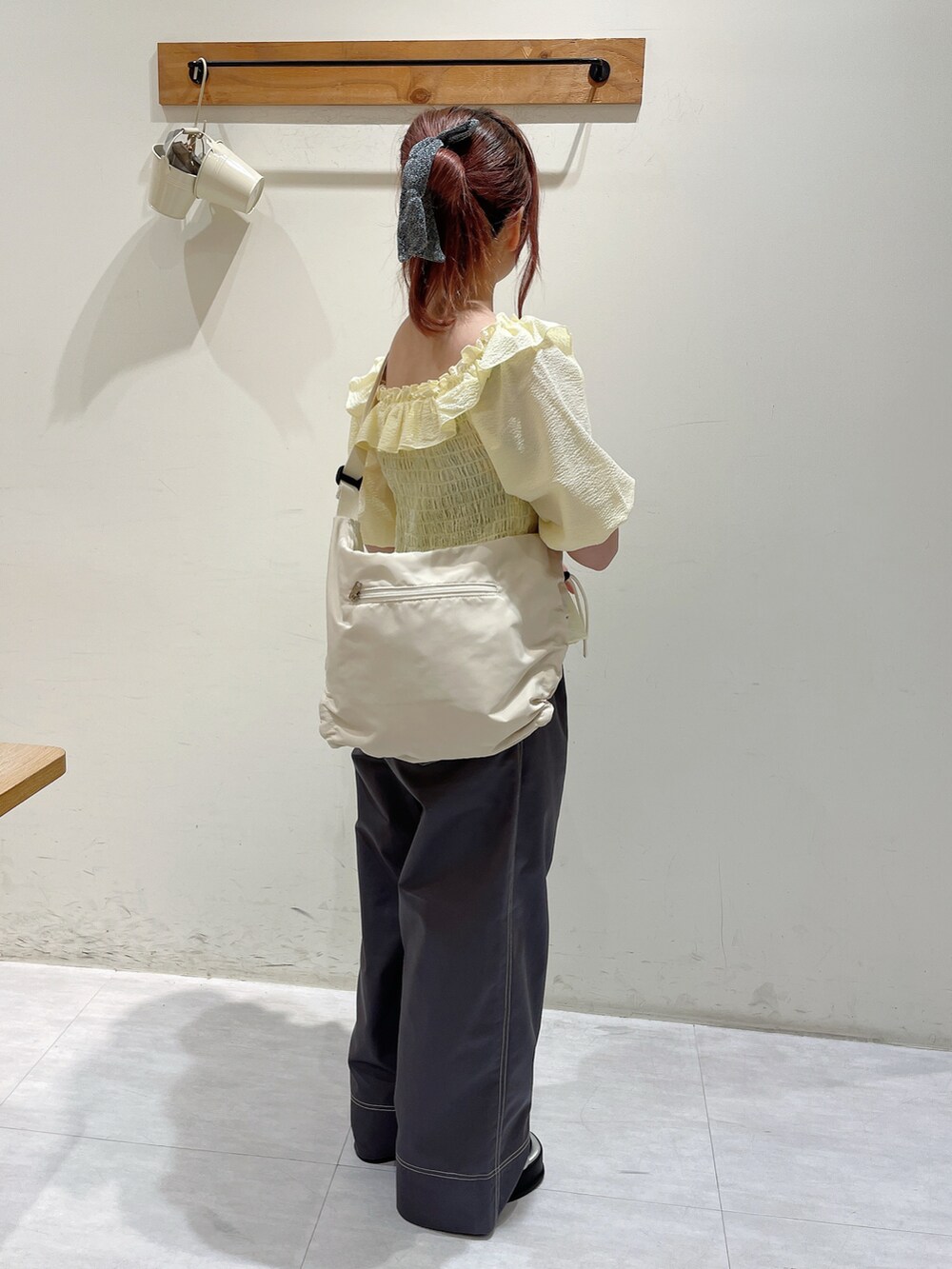 イエロー系のシャツ/ブラウス、ブラック系のパンツ、ホワイト系のハンドバッグを着用したレディースの春コーディネートの2枚目の写真