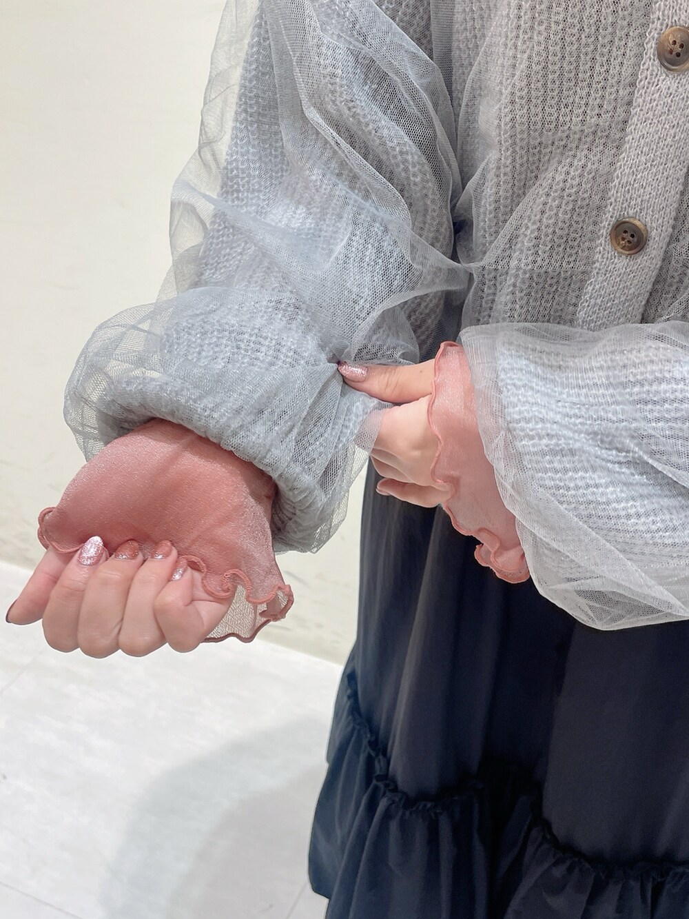 グレー系のカーディガン/ボレロ、ピンク系のTシャツ/カットソー、ブラック系のスカートを着用したレディースの秋コーディネートの4枚目の写真