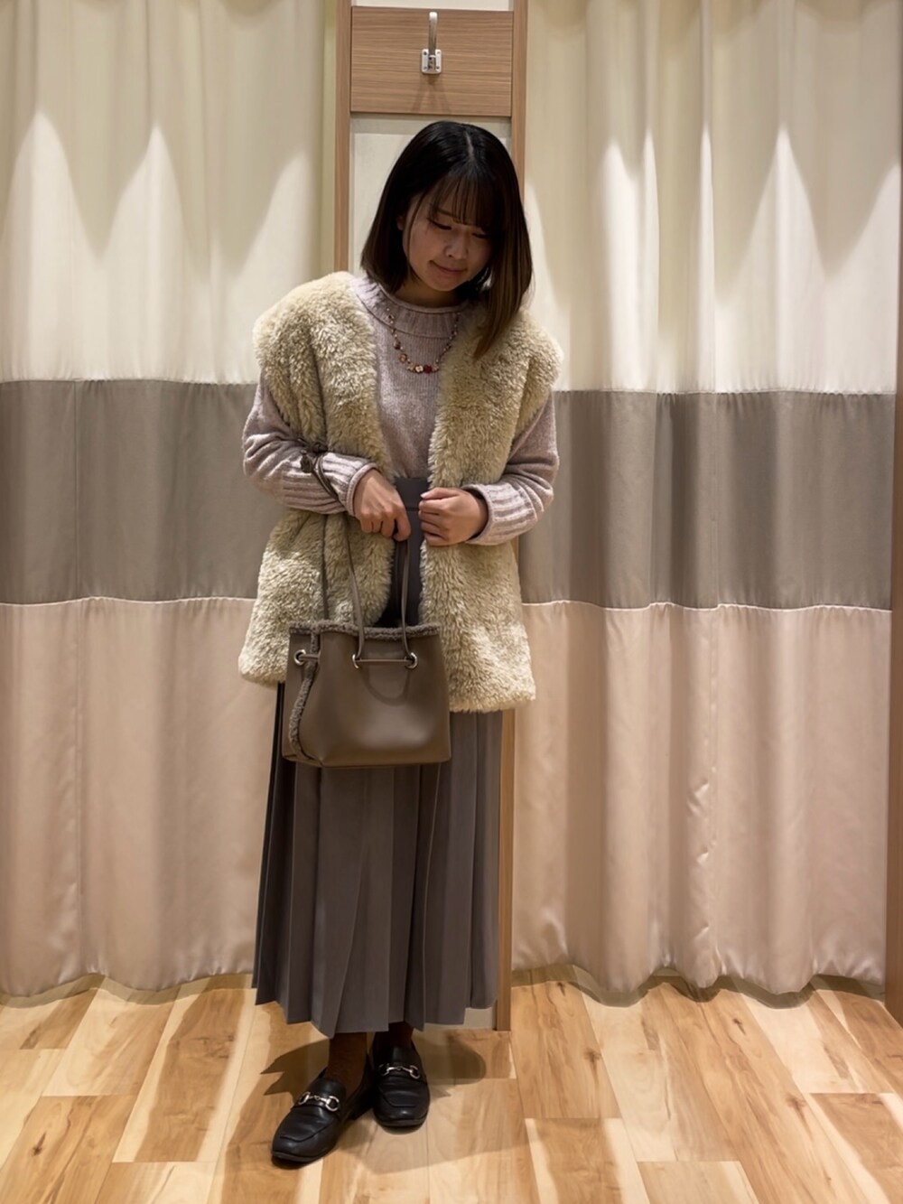 ホワイト系のブルゾン、ピンク系のニット/セーター、グレー系のスカートを着用したレディースの冬コーディネートの2枚目の写真