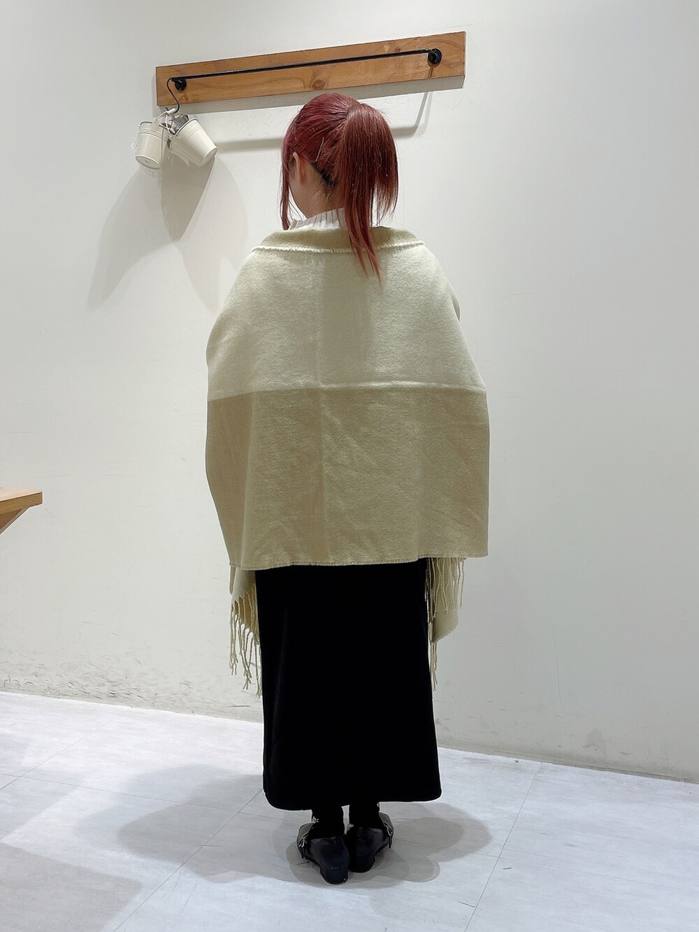 ホワイト系のニット/セーター、ブラック系のスカート、イエロー系のストール/ショールを着用したレディースの秋コーディネートの3枚目の写真